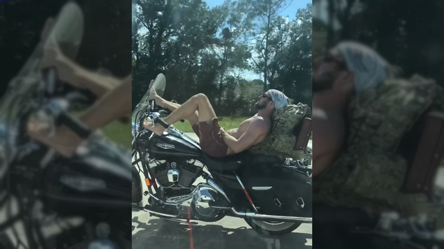 Shirtless man lies back and steers motorcycle with feet on Florida interstate