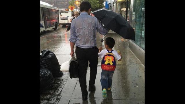 Photo of soaked father holding umbrella over young son goes viral