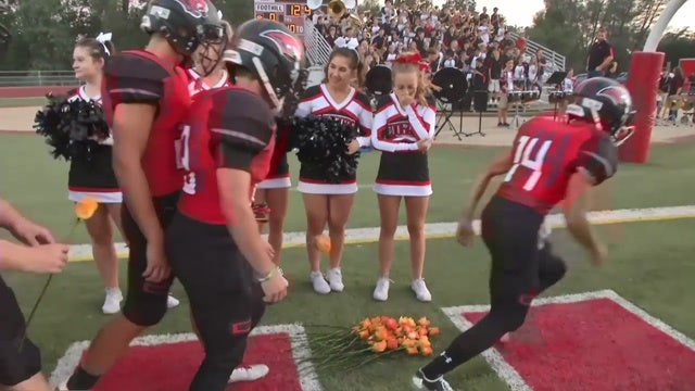 High school football team greets cheerleader battling leukemia with roses
