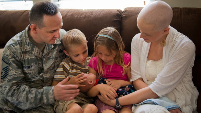 79466f4b-Father, mother battling cancer, and kids look over newborn baby