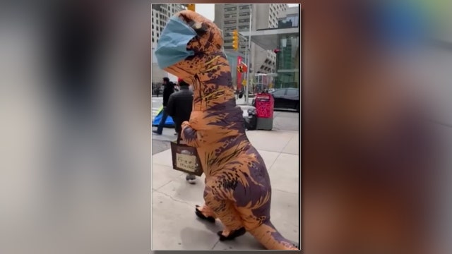 A mother and daughter dress up as dinosaurs to hand out homemade face masks