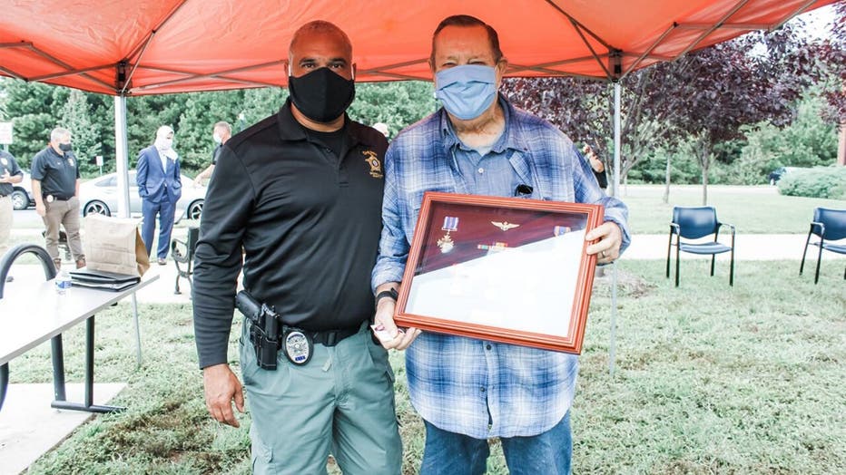 Vet poses with detective and medals