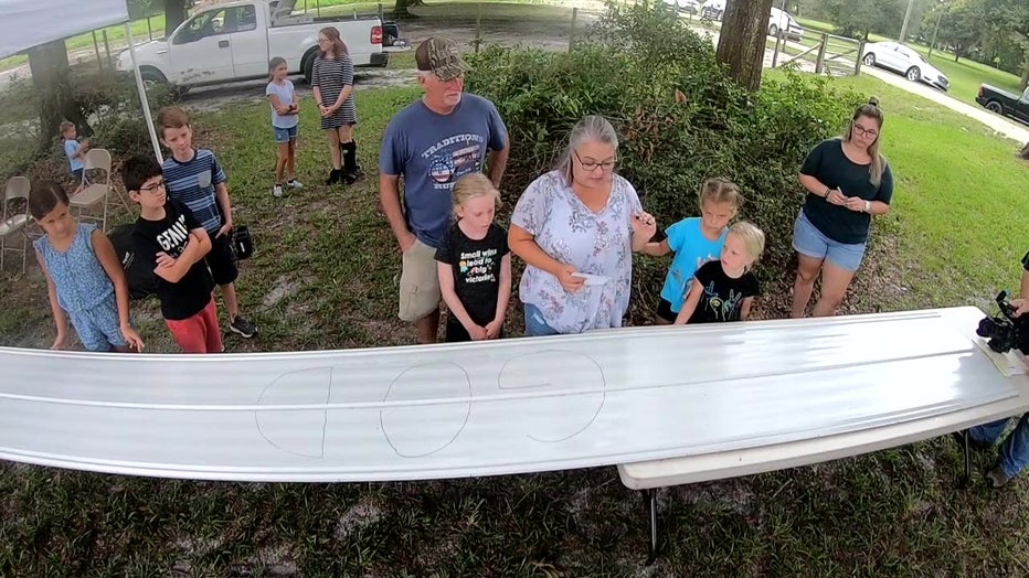 Perkins family with steel beam that has God written on it. 