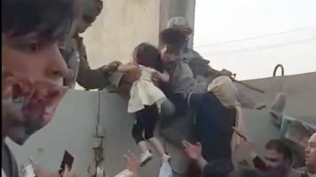 Young child hoisted over wall amid chaos at Kabul airport