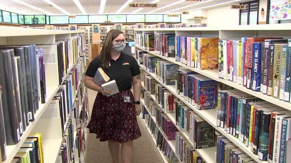 Abigail Davis, a public service librarian at St. Pete Beach Library walking between the bookshelves.