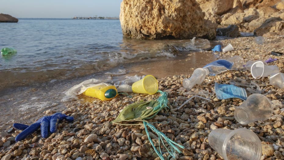 Plastic debris and face masks on the beach in surf zone