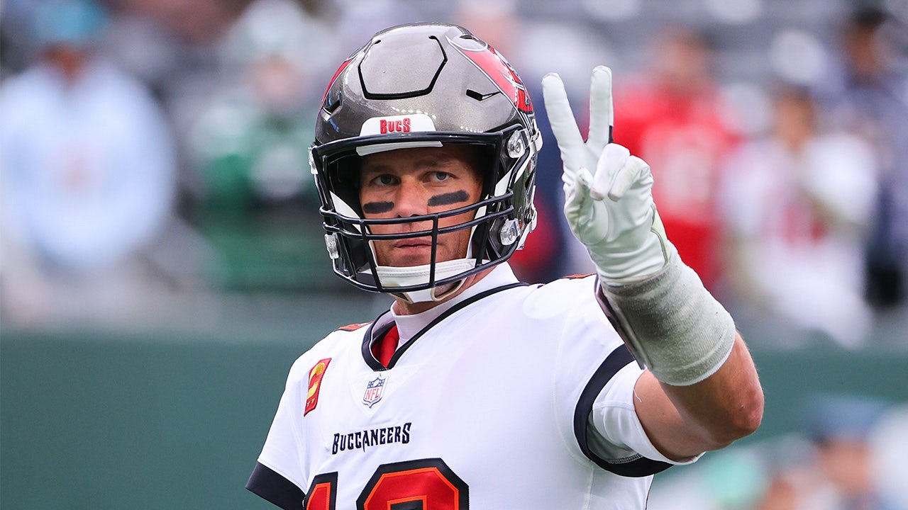 Tom Brady throwing a peace sign in the air during a game