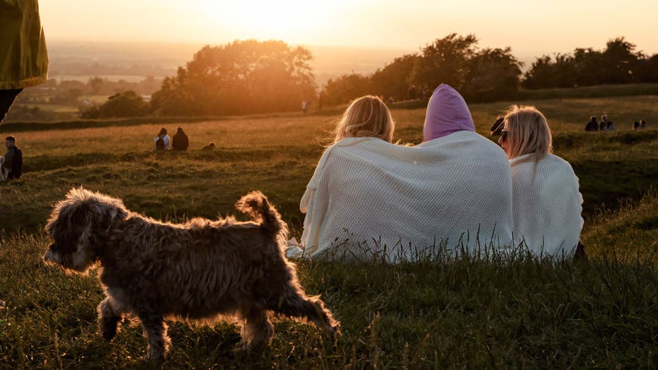 Three women siting and  watching the sunset while a small