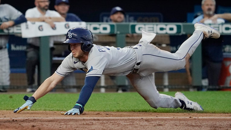 Brett Phillips #35 of the Tampa Bay Rays dives into home to score on a Yandy Diaz three-run double in the fourth inning against the Kansas City Royals at Kauffman Stadium on July 22, 2022 in Kansas City, Missouri.