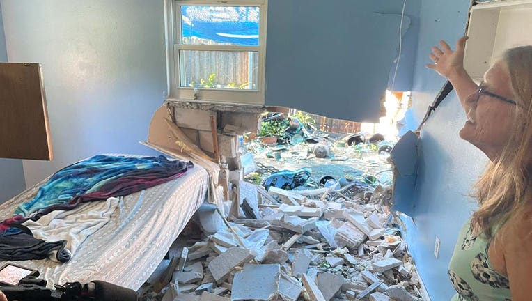 Gaping hole left behind in Pinellas Park home after stolen car crashes into residence. Concrete blocks and debris are scattered inside and outside.