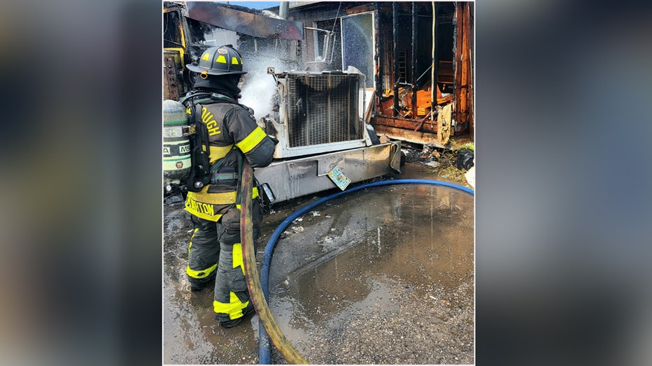 Firefighter uses hose to put out flames on semi-truck