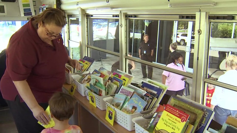 Woman hands child a book on the Summer Book Bus