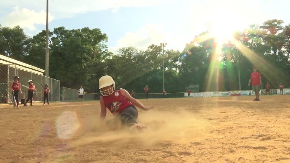 West Pasco Girls' Softball team player sliding onto plate.