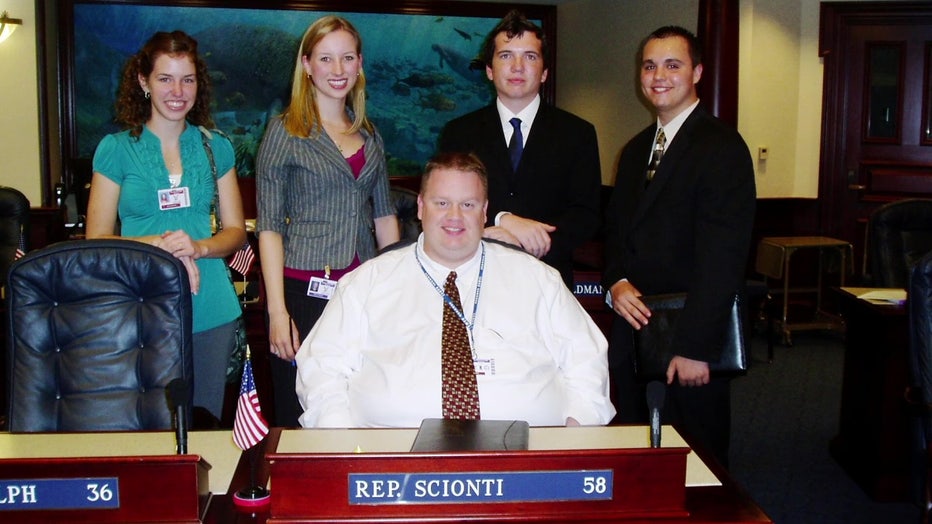 Tony Pirotta and students behind desk. 