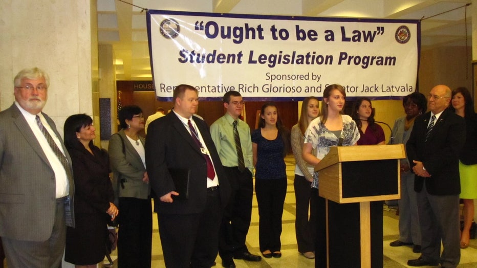 Tony Pirotta and students with 'Ought To Be A Law' sign. 