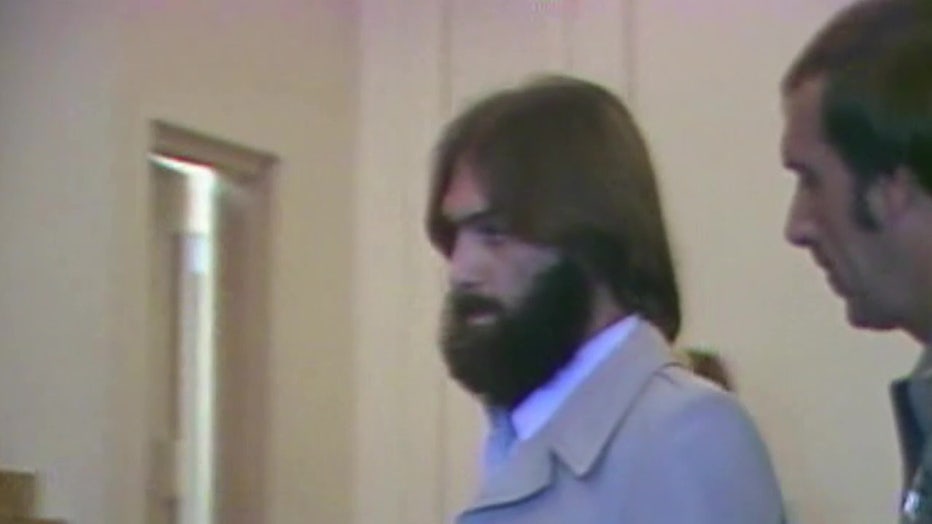 Serial killer Billy Mansfiled Jr. being walked out of a room by law enforcement officers. 