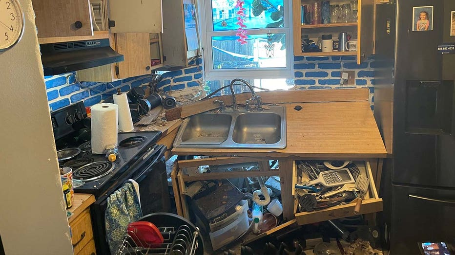 Photo: Kitchen counter near toppled over and walls are damaged following car crash 