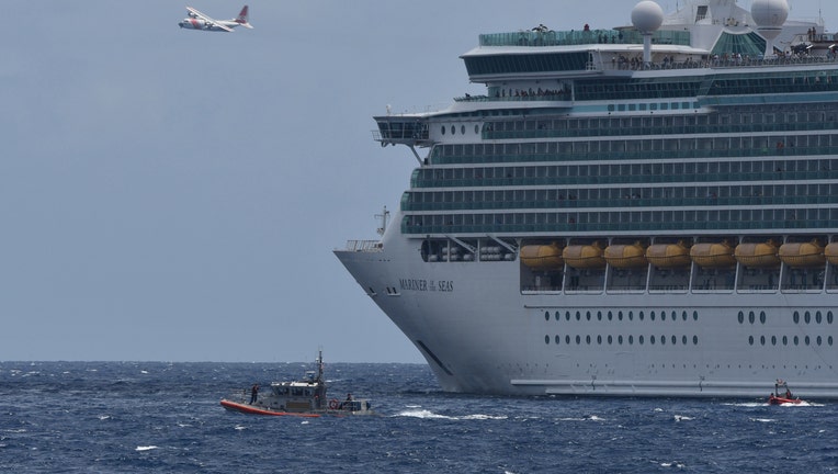 Coast Guard boat in the water and plane in the air next to cruise ship.