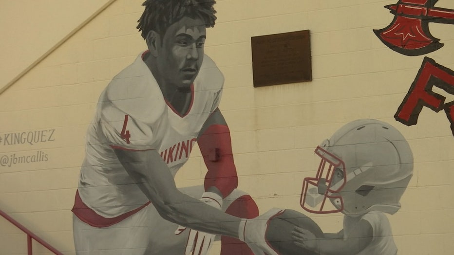Photo: Mural of Jacquez Welch at Northeast High School shows the former football player handing a football to a child wearing football helmet