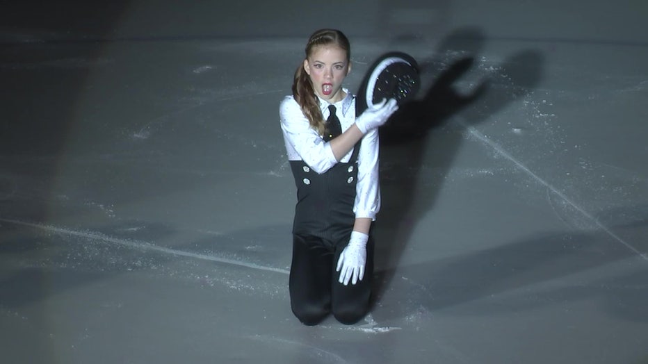 Female figure skater on ice with hat.