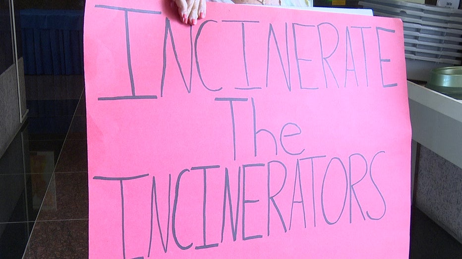 A protester holds a sign saying incinerate the incinerator.
