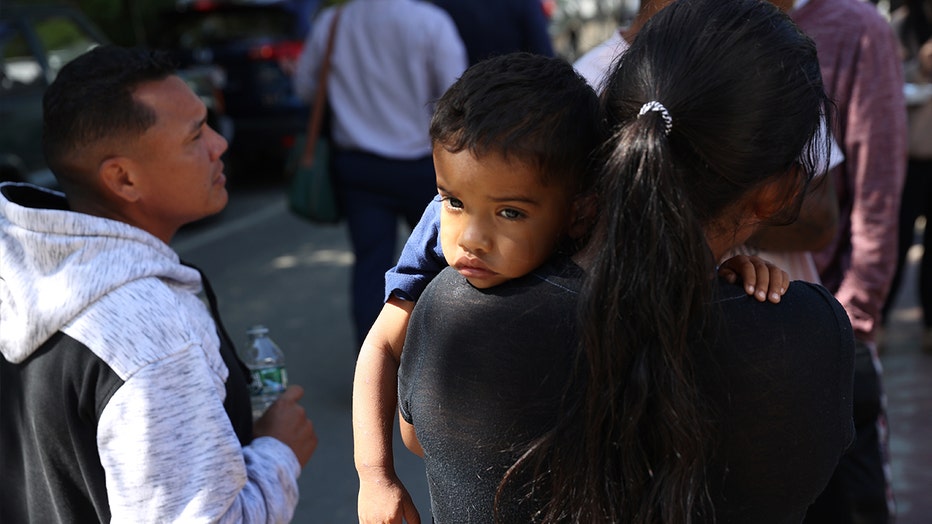 Phot: A mother and child spent some time outside the St. Andrew's Parrish House where migrants were being fed lunch with donated food from the community.