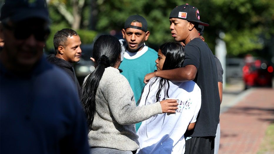 Photo: A group of migrants huddle on a sidewalk in front of St. Andrews Episcopal Church. 
