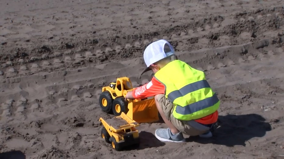 Photo: Owen plays with his toy-sized Cat vehicles at a construction site.