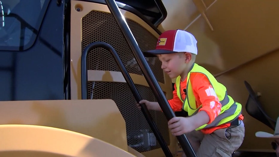 Photo: Owen climbs up ladder to get to the driver's seat of a construction vehicle.