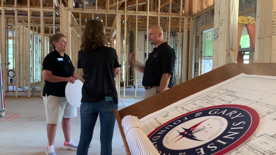 Army First Sgt. John Borders talks with two women as his new home is being constructed.