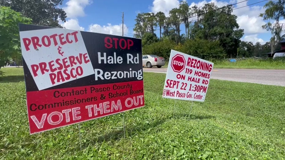 Signs protesting proposed developments in Pasco County along a grassy median. 