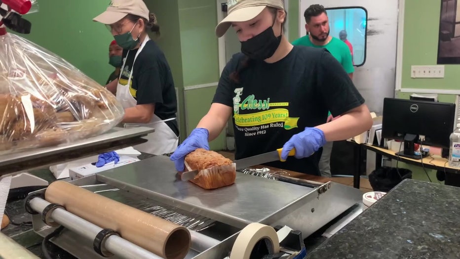 Employee slices bread at Alessi Bakery. 