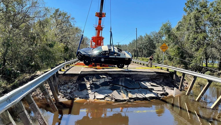 Photo: Crews pull a Florida Highway Patrol patrol car from floodwaters with a crane in Hardee County.