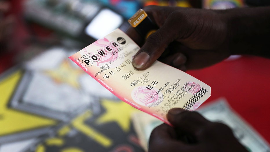 A customer holds a Powerball ticket at the Shell Gateway store in Boynton Beach, Florida. (Photo by Joe Raedle/Getty Images)