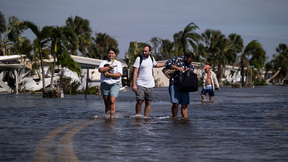 Photo: People carry their belongings wade through water on a flooded neighborhood in the aftermath of Hurricane Ian in Fort Myers, Florida on September 29, 2022. 