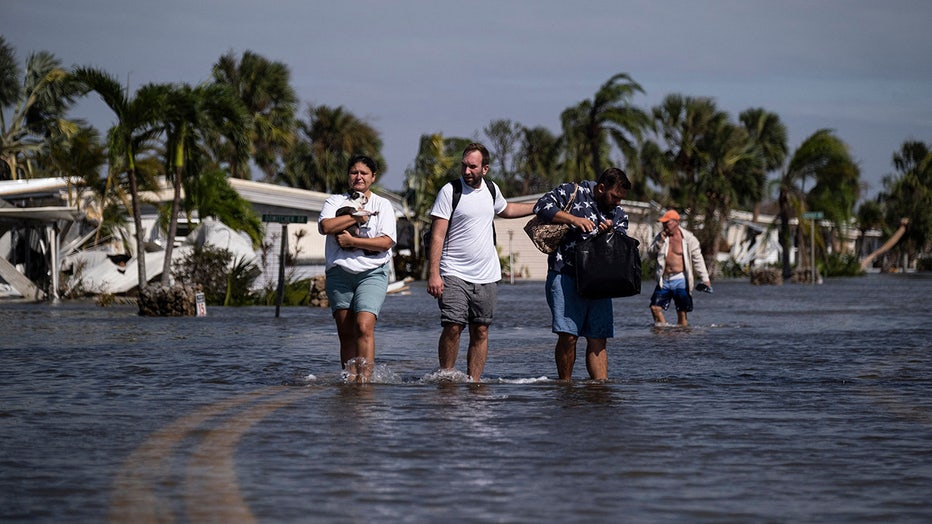 Photo: People carry their belongings wade through water on a flooded neighborhood in the aftermath of Hurricane Ian in Fort Myers, Florida on September 29, 2022.
