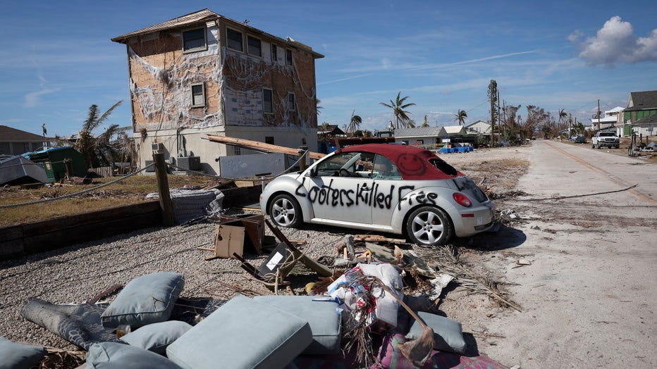 Photo: A warning to looters is painted on the side of a car destroyed during Hurricane Ian on October 03, 2022 in Pine Island, Florida. 