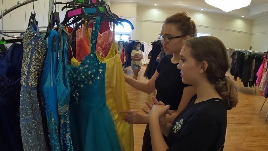 A mother and daughter look through rack of dresses. 