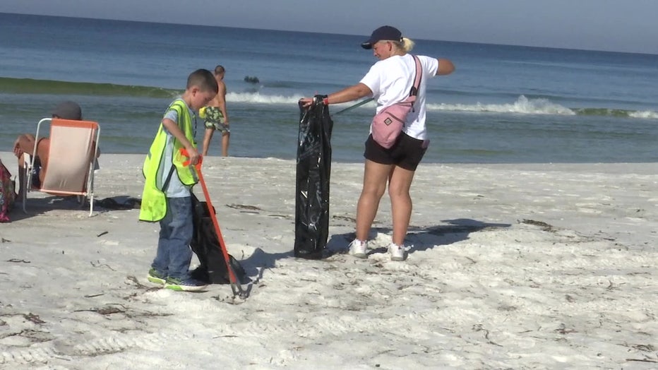 A woman and child clean up the beach. 
