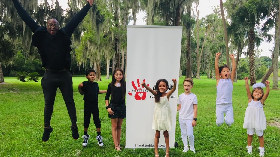 Sean Roberts poses with children in front of sign.