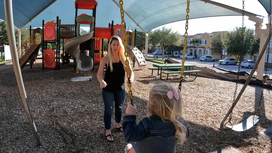 Woman pushing child on a swing. 