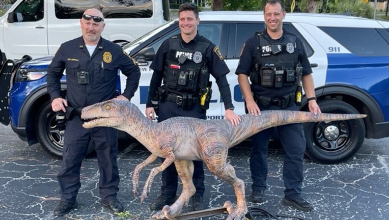 Three police officers pose with an animatronic dinosaur. 