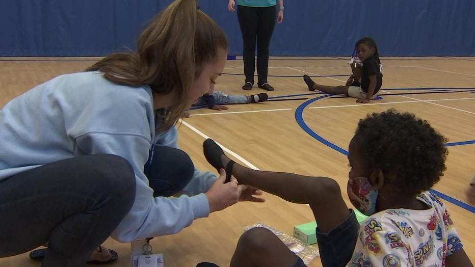 Ballet instructor helps fit students with new ballet shoes.