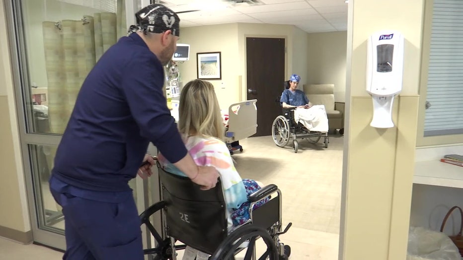 A medical professional wheels Rebekah into Alexis Gould's room.