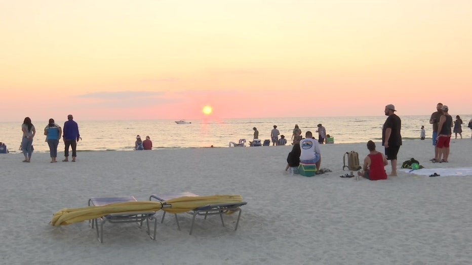 Beachgoers enjoy the sunset despite a red tide bloom.