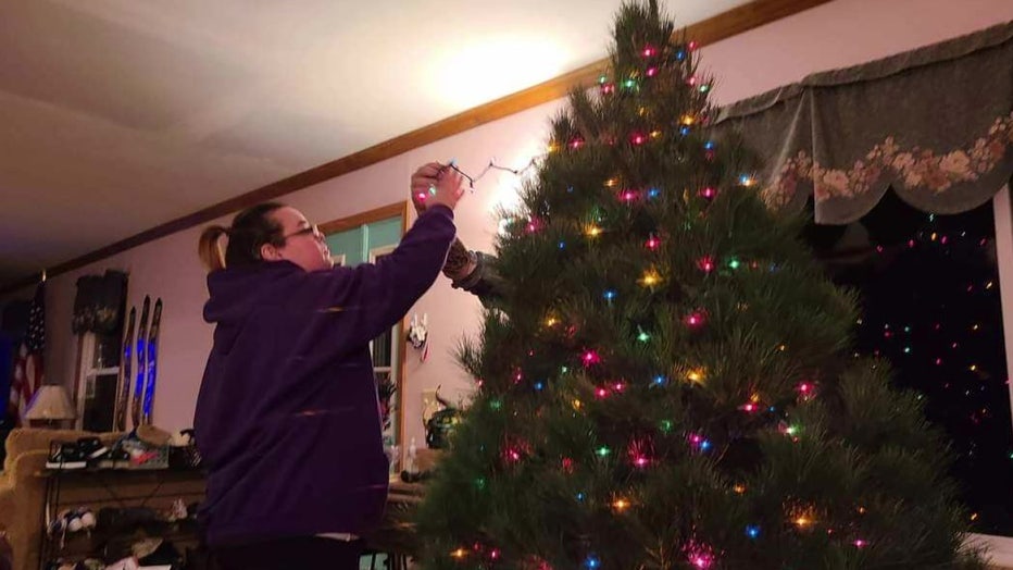 A woman decorates a Christmas tree.