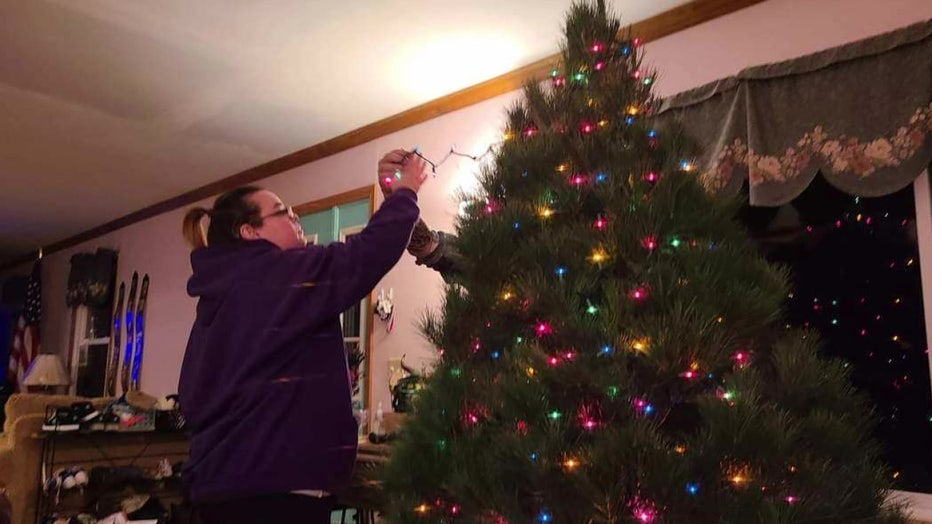 A woman decorates a Christmas tree. 