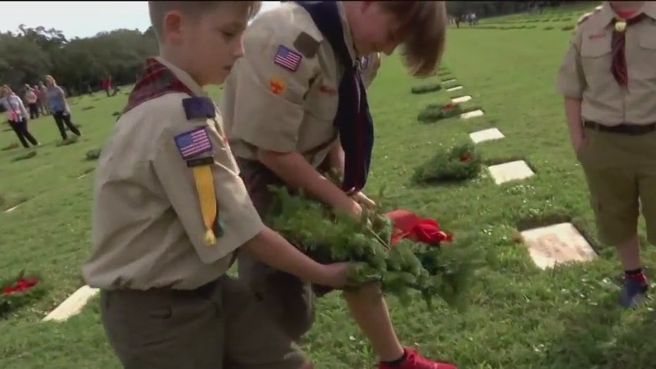 Cub scouts lay wreaths on headstones at Bay Pines National Cemetery. 