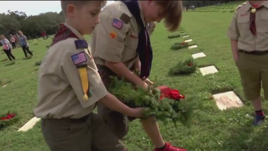 Cub scouts lay wreaths on headstones at Bay Pines National Cemetery.