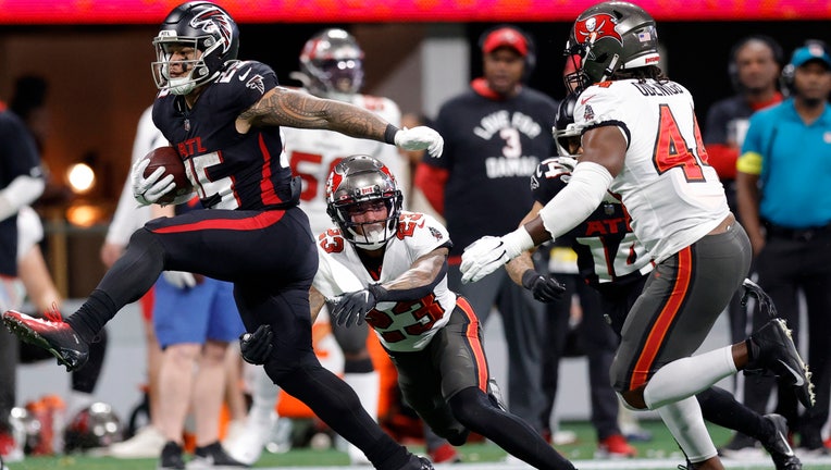 Tyler Allgeier #25 of the Atlanta Falcons runs the ball against Sean Murphy-Bunting #23 and Ifeadi Odenigbo #44 of the Tampa Bay Buccaneers during the third quarter at Mercedes-Benz Stadium on January 08, 2023 in Atlanta, Georgia. (Photo by Alex Slitz/Getty Images)